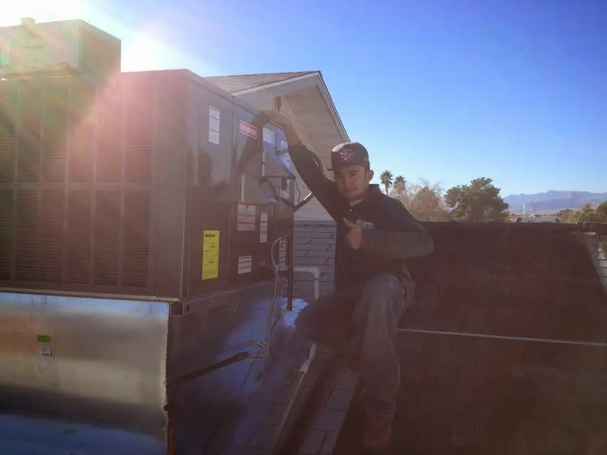 HVAC technician performing AC Tune-Up on a rooftop unit in Spring Arbor
